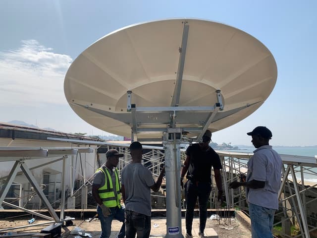 Ingénieurs à côté d'une antenne satellite bande C de 2,4 m sur le toit de la station du câble ACE à Lumley Beach, Freetown