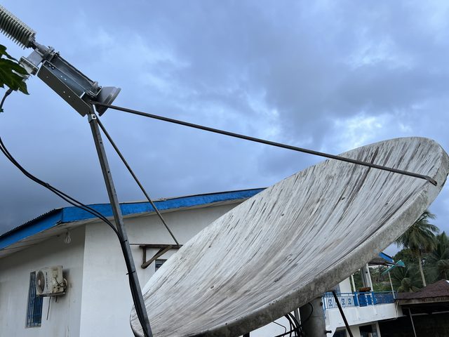 Antenne satellite de 2,4 m au bureau de Plan International dans le comté de Bomi, sous un ciel d'orage