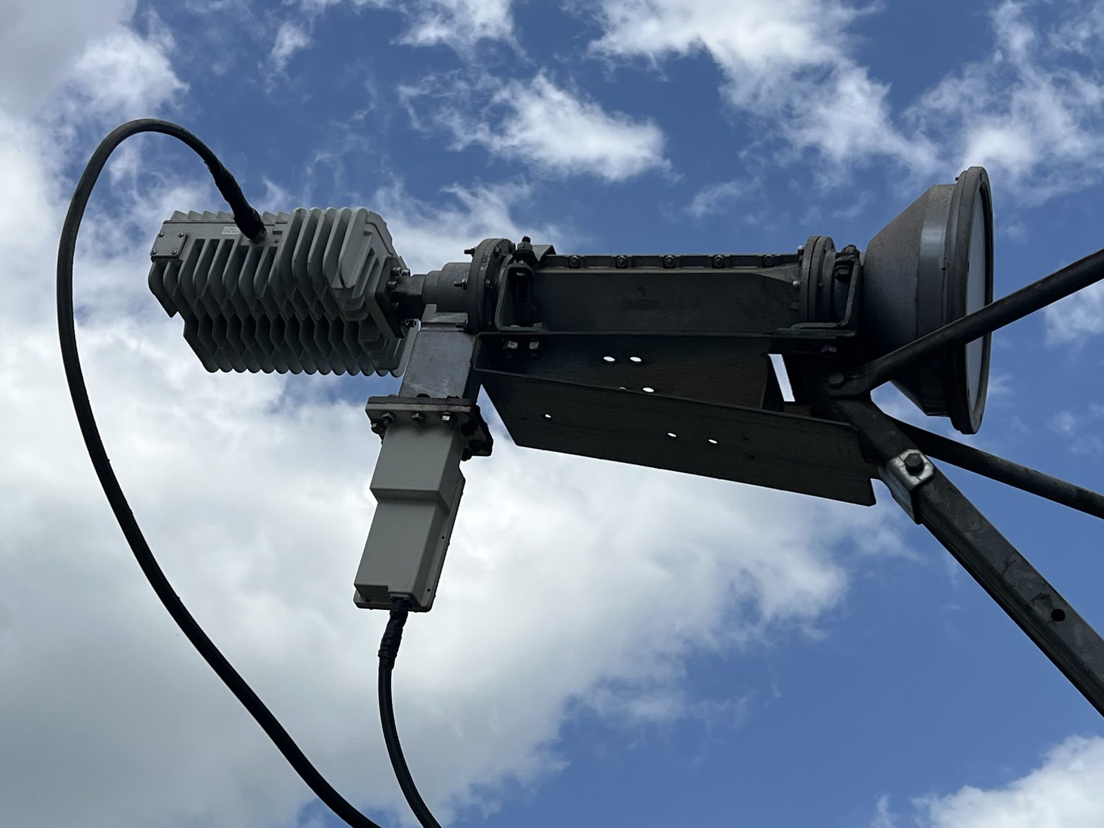 Close view of the feed horn, BUC and LNB on the feed support arm of the Bomi antenna, against a blue sky