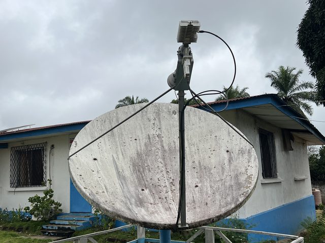Antenne satellite sur pied clôturé au bureau de terrain de Plan International dans le comté de Lofa, le jour de la migration vers SES4