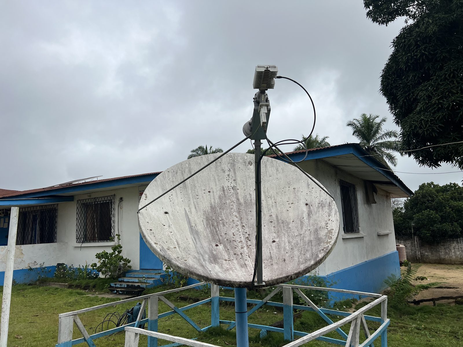 Satellite antenna on a fenced pedestal in front of the Plan International field office building in Lofa County