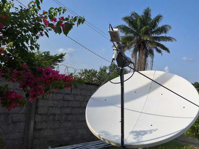 Antenne satellite dans l'enceinte de Plan International à Ganta, comté de Nimba, à côté d'un bougainvillier
