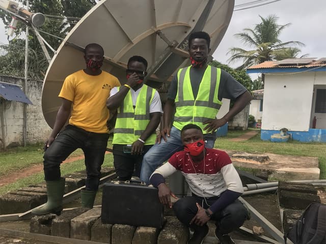 Quatre ingénieurs de terrain devant l'antenne bande C de 2,4 m au bureau du HCR à Zwedru, comté de Grand Gedeh