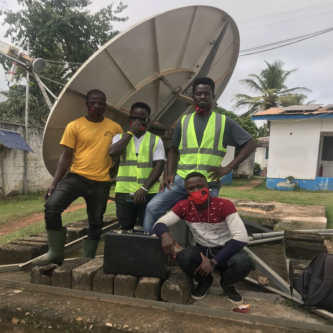 Four Global IT Firm field engineers in front of a 2.4 m C-Band VSAT antenna