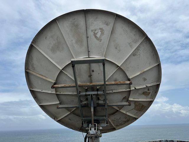 Arrière de l'antenne satellite de 3,8 m de l'UNICEF sur le toit de One UN House, avec l'océan en arrière-plan