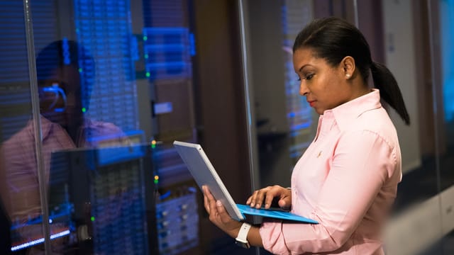 Engineer using a tablet computer beside server racks in a data centre