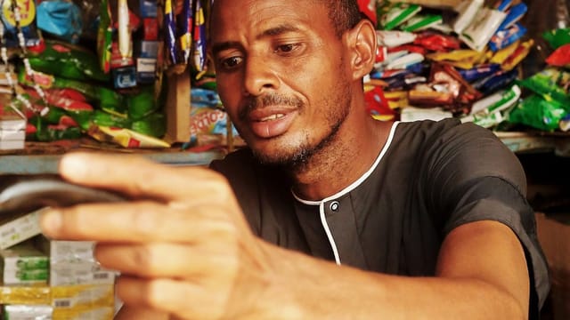 Commerçant utilisant une application mobile sur son smartphone dans une petite boutique