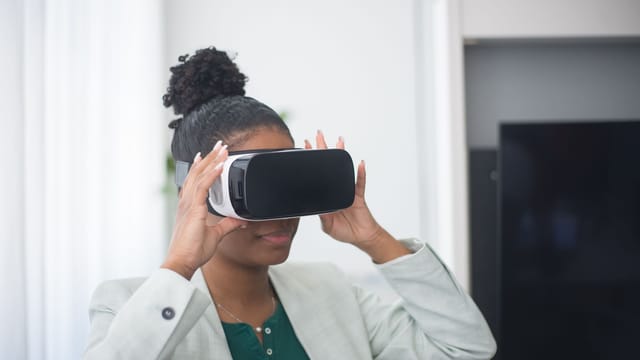 Professional in a light blazer trying on a virtual reality headset in an office