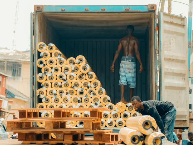 Workers loading rolls of fabric into a shipping container in Kumasi, Ghana