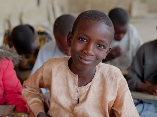 Élève souriant à son pupitre dans une salle de classe au Nigeria