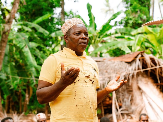 Community leader speaking to residents at an outdoor village meeting