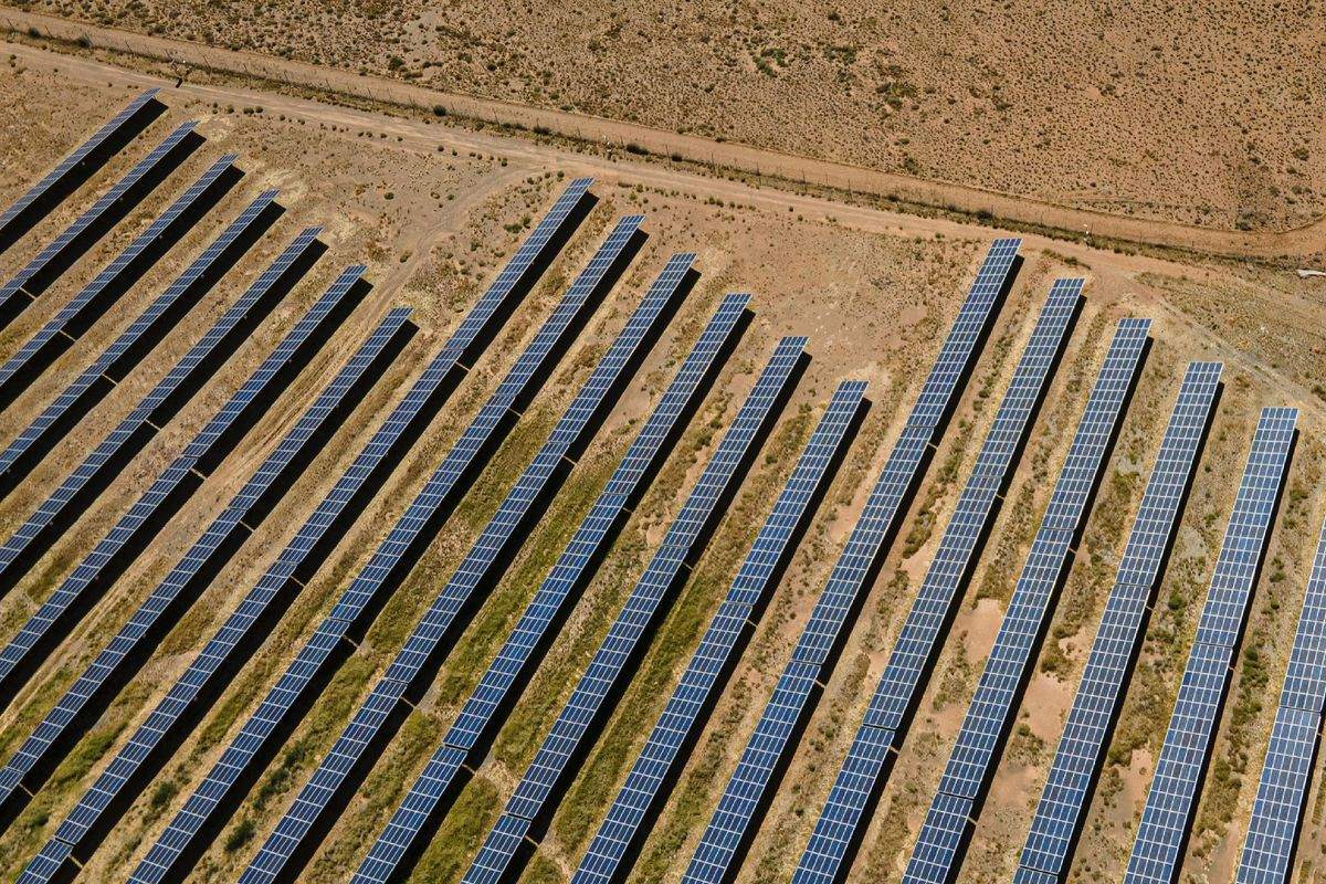 Aerial view of rows of ground-mounted solar panels on dry land