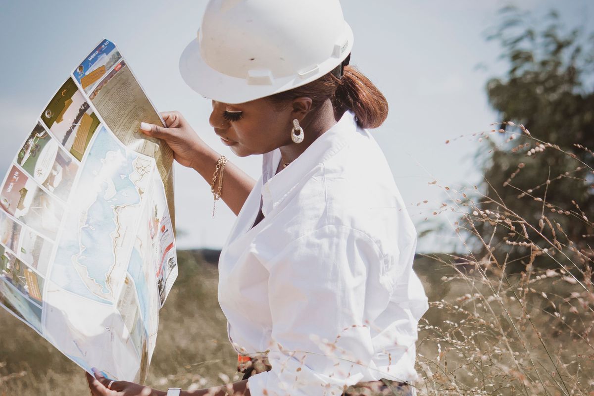 Engineer in a hard hat reading a map in an open field