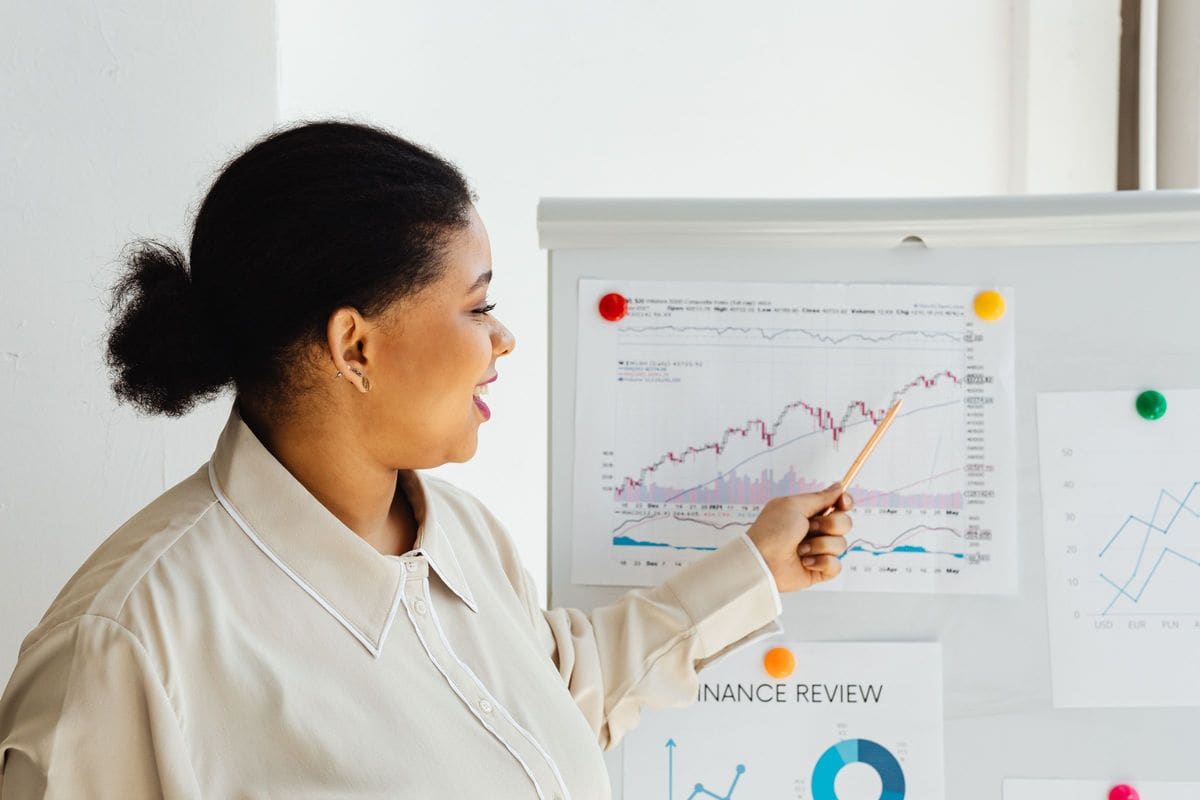 Woman pointing at data charts on a whiteboard while explaining trends