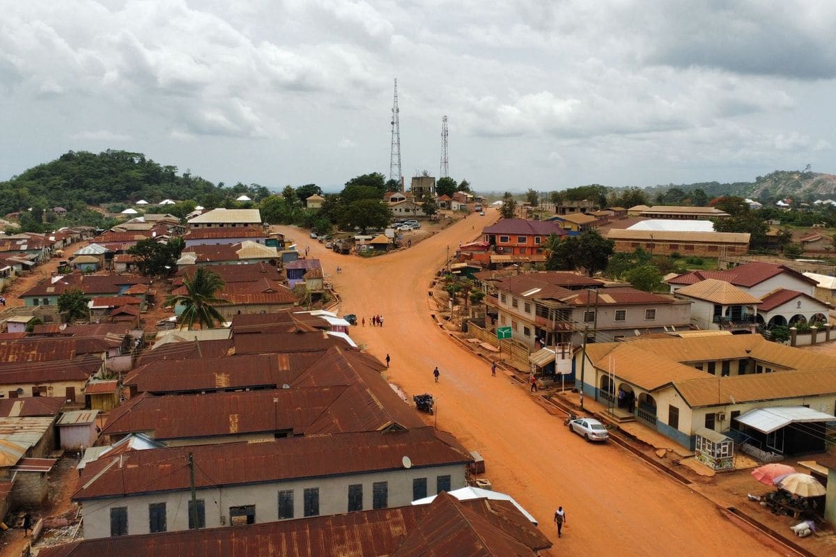Aerial view of an African town with red-roofed buildings, dirt roads and communication masts