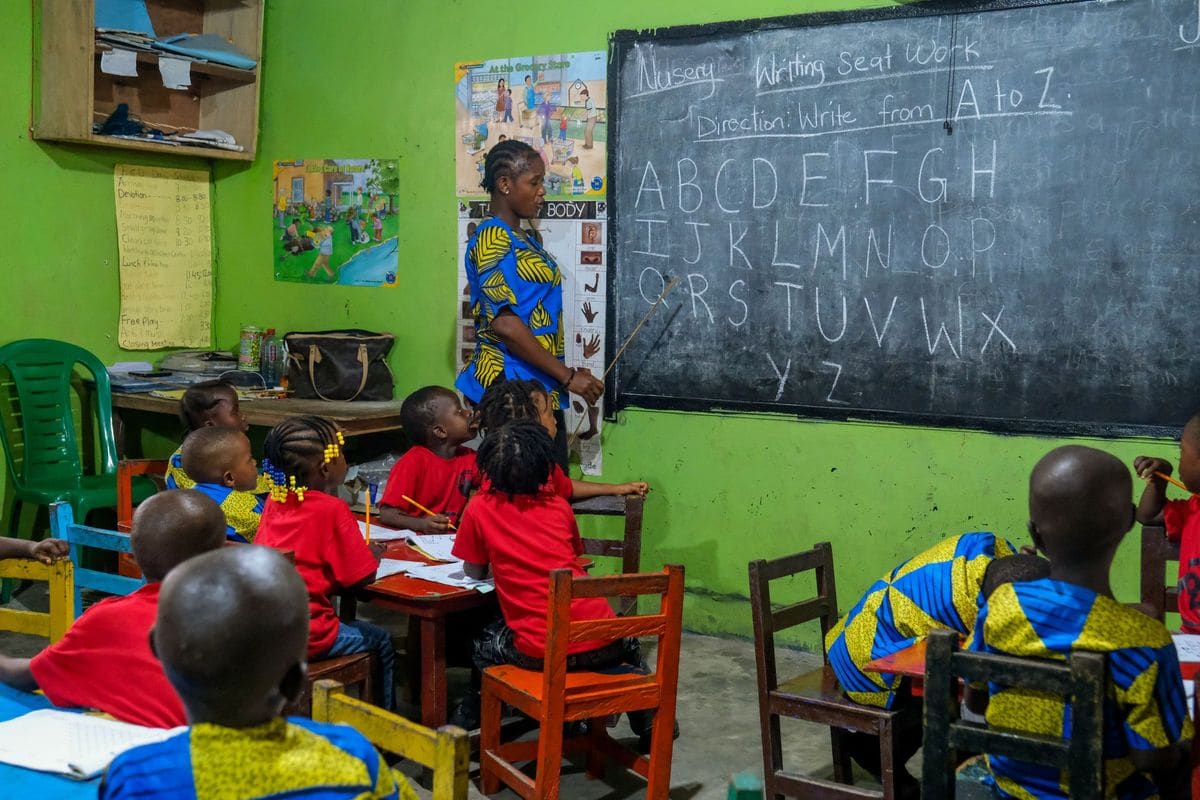Teacher leading an alphabet lesson for young pupils in a Liberian classroom