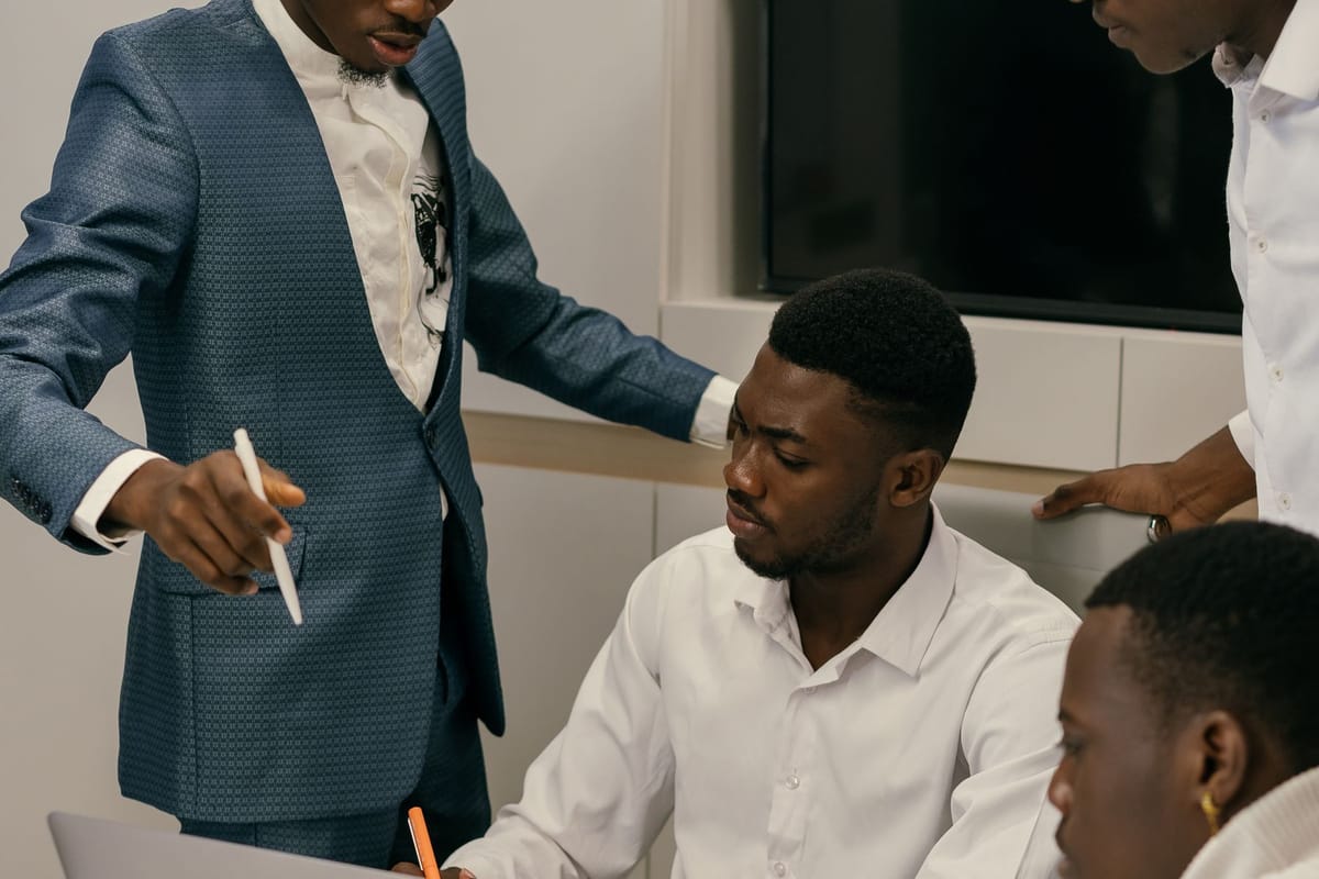 Team lead pointing at documents while colleagues review them at a laptop