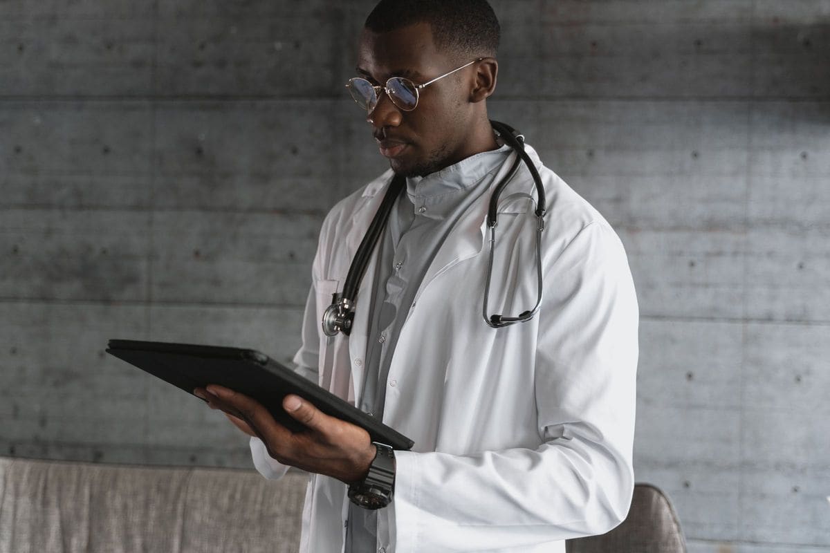 Doctor in a white coat with a stethoscope using a tablet