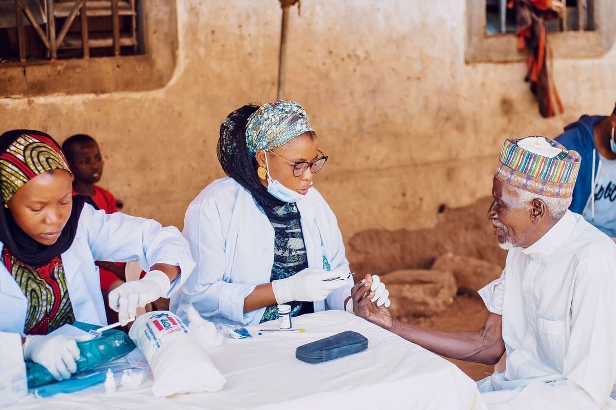 Health workers attending to an elderly man at a community medical outreach in Kaduna, Nigeria