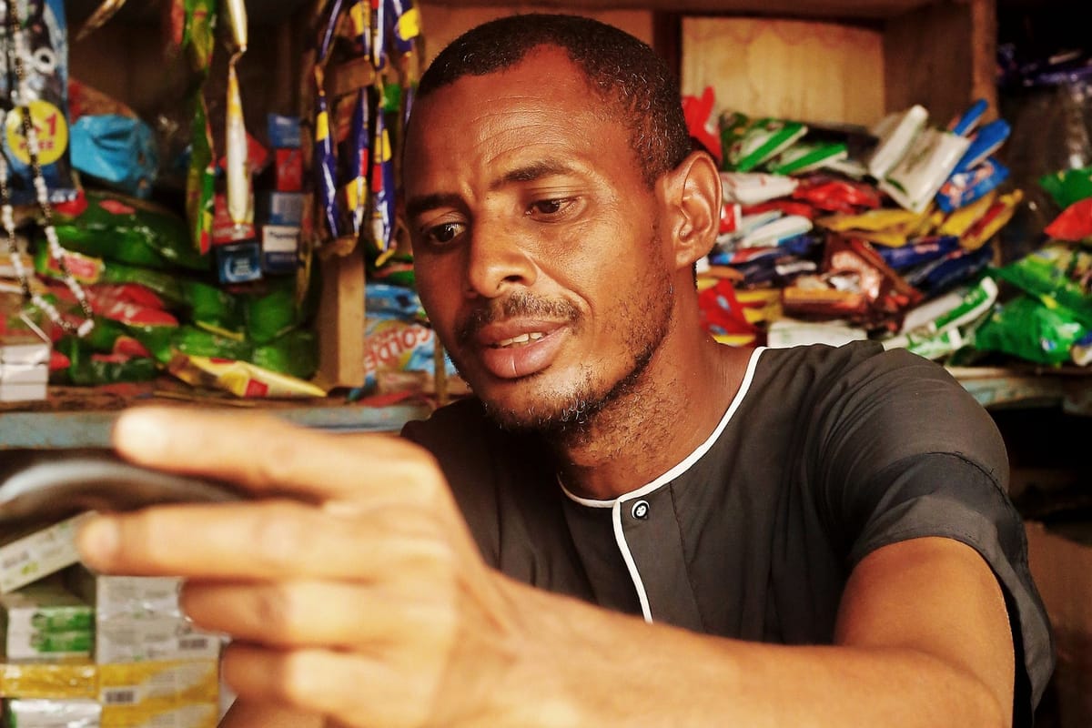 Shopkeeper using a smartphone in a small grocery store